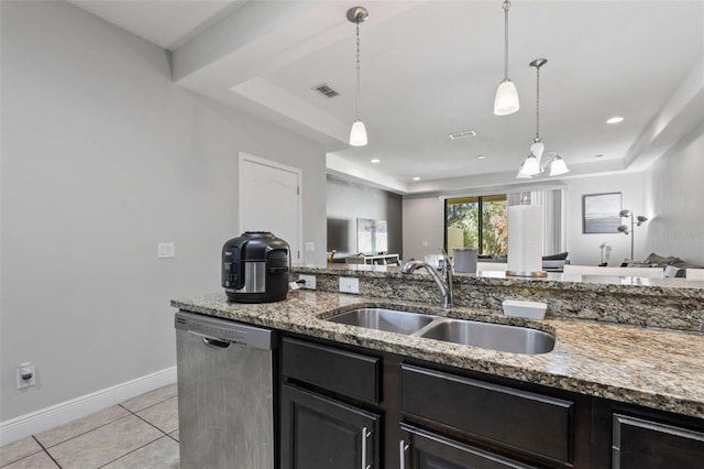 kitchen with pendant lighting, dishwasher, sink, a tray ceiling, and light stone counters