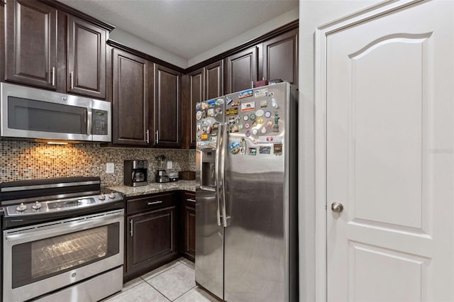 kitchen with dark brown cabinets, light tile patterned floors, backsplash, and appliances with stainless steel finishes