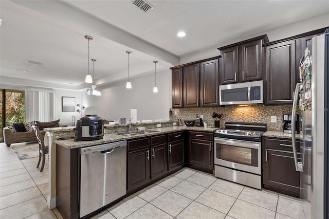 kitchen with kitchen peninsula, dark brown cabinetry, stainless steel appliances, and decorative light fixtures