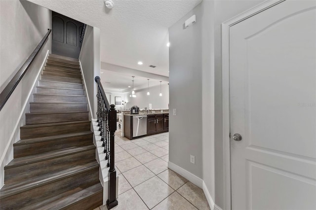 stairway with a textured ceiling and tile patterned floors