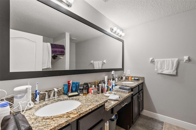 bathroom with tile patterned flooring, vanity, and a textured ceiling