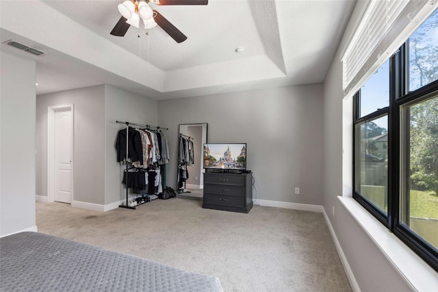 bedroom with light carpet, a raised ceiling, and ceiling fan