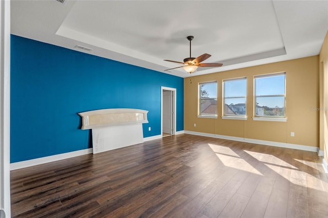 unfurnished living room with ceiling fan, hardwood / wood-style flooring, and a tray ceiling