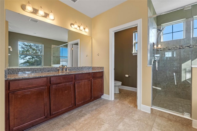 bathroom with toilet, walk in shower, a wealth of natural light, and vanity