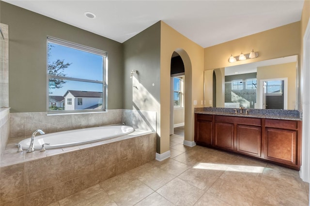 bathroom featuring tiled bath, plenty of natural light, tile patterned floors, and vanity