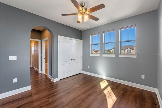 unfurnished bedroom with a closet, ceiling fan, and dark wood-type flooring