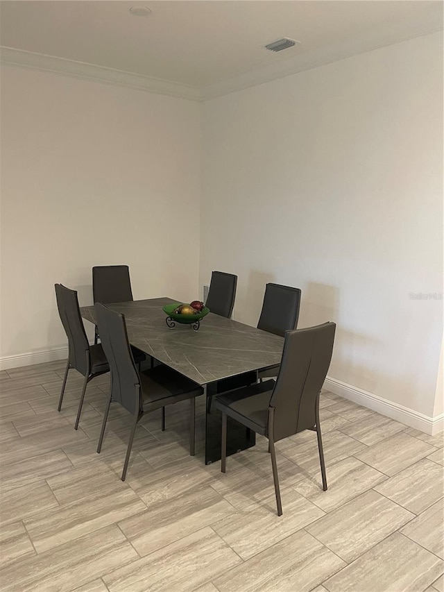 dining room with crown molding and light hardwood / wood-style floors