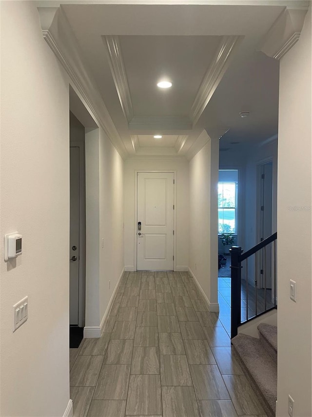 hall with a tray ceiling and ornamental molding