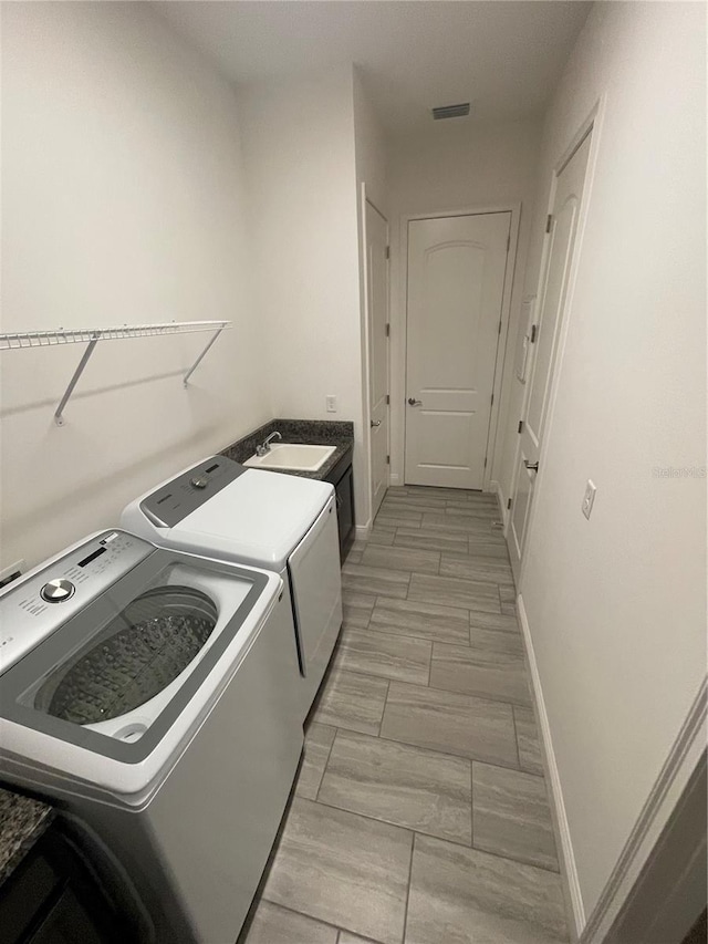 clothes washing area with light hardwood / wood-style floors, washing machine and dryer, and sink