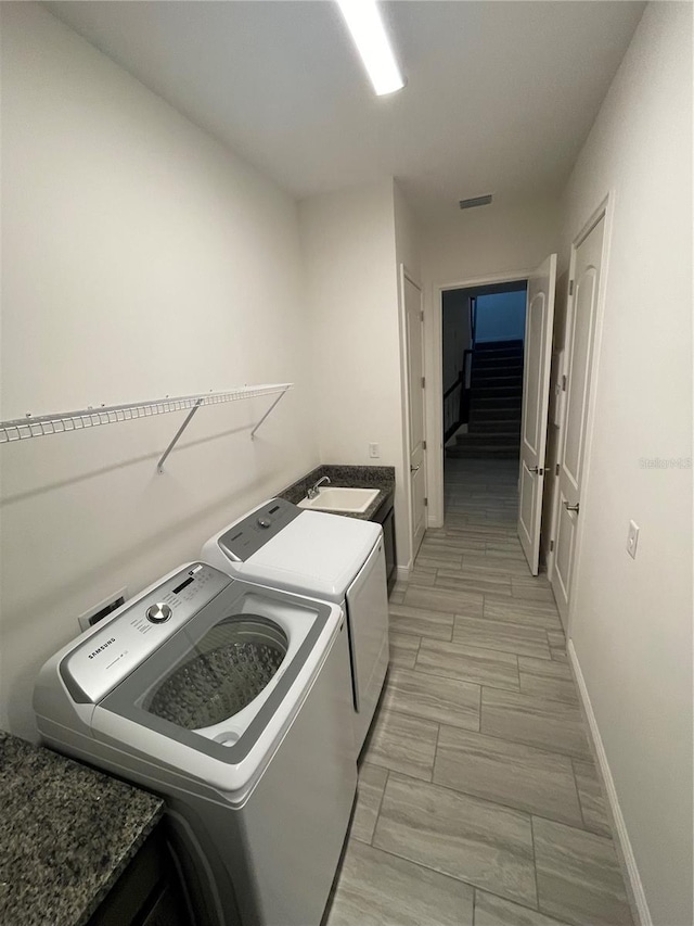 washroom featuring washer and clothes dryer, sink, and light hardwood / wood-style flooring