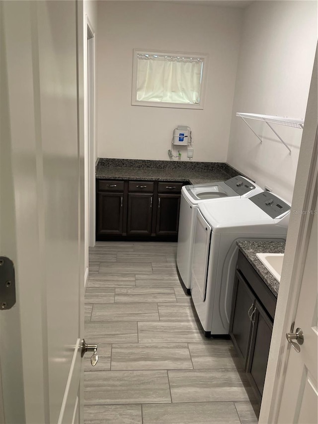 laundry area featuring cabinets, separate washer and dryer, and light hardwood / wood-style flooring