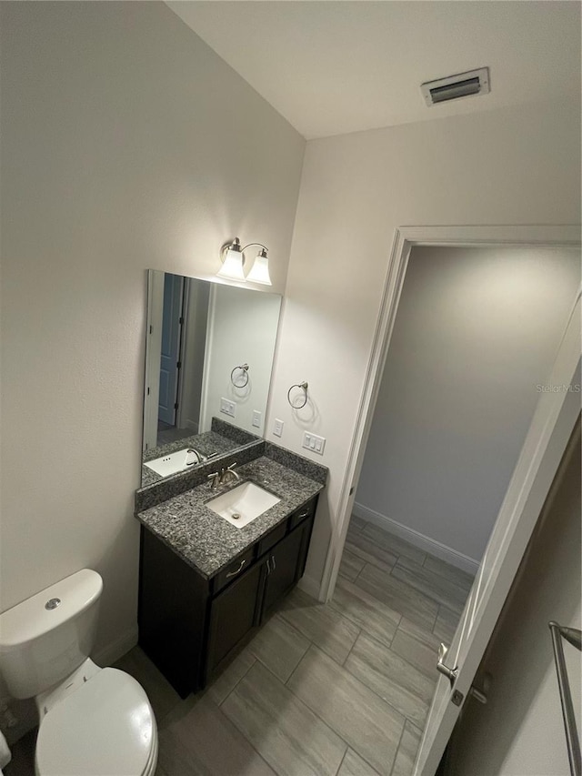 bathroom featuring vanity, toilet, and lofted ceiling