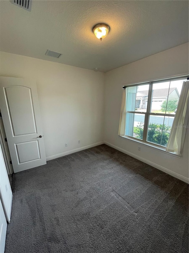 carpeted spare room with a textured ceiling