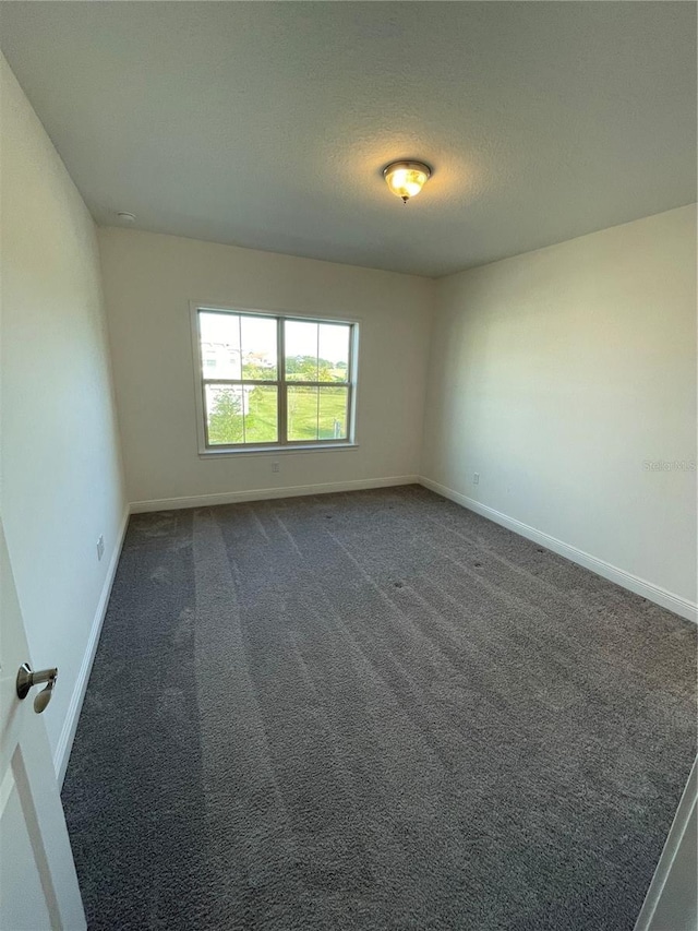 spare room with dark carpet and a textured ceiling