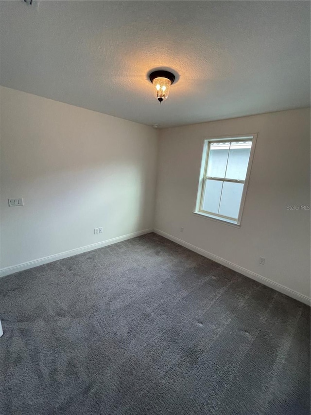 spare room with dark carpet and a textured ceiling