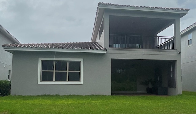 rear view of house featuring a yard and a balcony