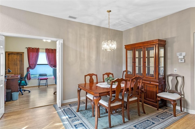 dining room featuring light wood-type flooring and a notable chandelier