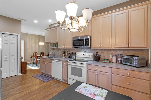 kitchen with pendant lighting, light hardwood / wood-style floors, white appliances, and a chandelier