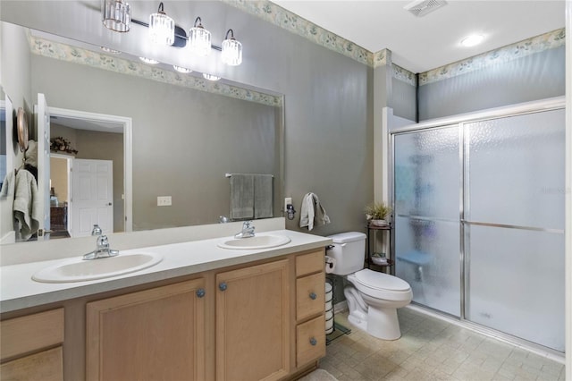 bathroom featuring a shower with door, vanity, and toilet