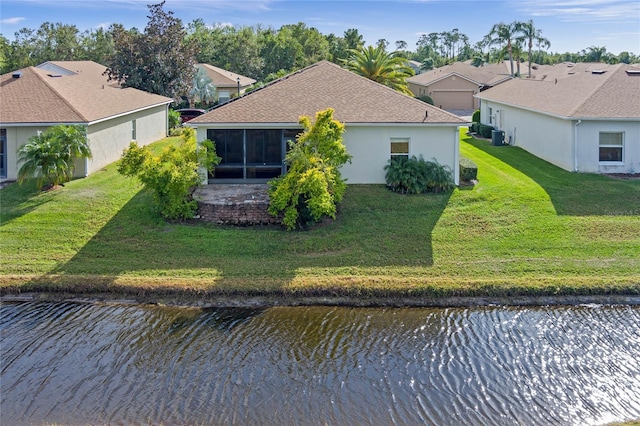 back of property with a lawn, a sunroom, and a water view