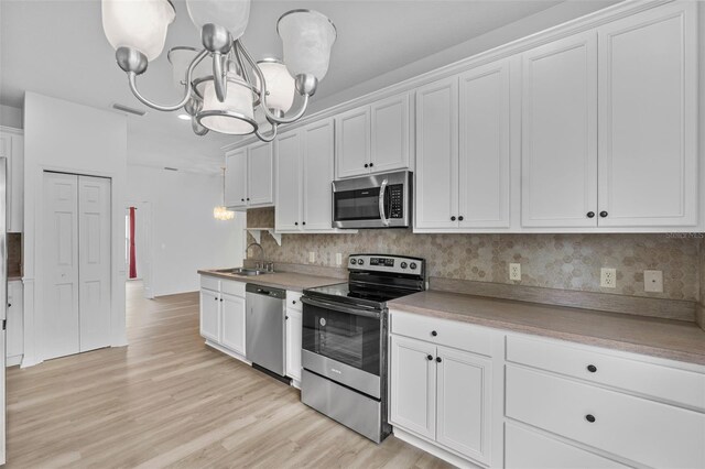 4112 Aberdeen Ln, Lake Wales, FL 33859 - kitchen with stainless steel appliances, a chandelier, backsplash, white cabinets, and light wood finished floors