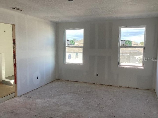 unfurnished room featuring plenty of natural light and a textured ceiling