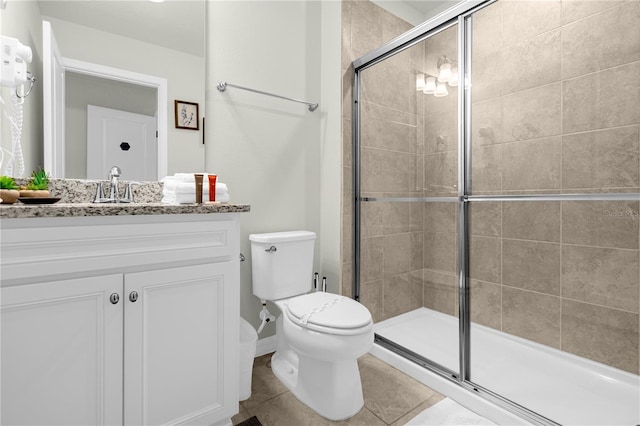 bathroom with toilet, vanity, tile patterned floors, and a shower with shower door