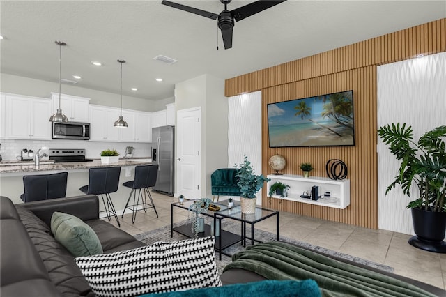 living room with ceiling fan, light tile patterned floors, and sink