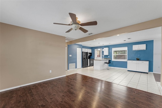 unfurnished living room featuring ceiling fan, light hardwood / wood-style floors, and sink