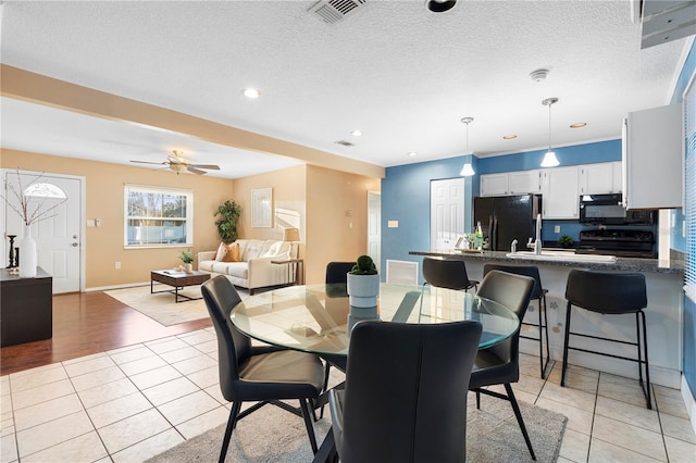 dining room with light tile patterned floors, a textured ceiling, and ceiling fan