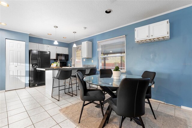 tiled dining space with crown molding, sink, and a textured ceiling