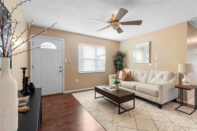 living room featuring ceiling fan, light hardwood / wood-style floors, and a textured ceiling