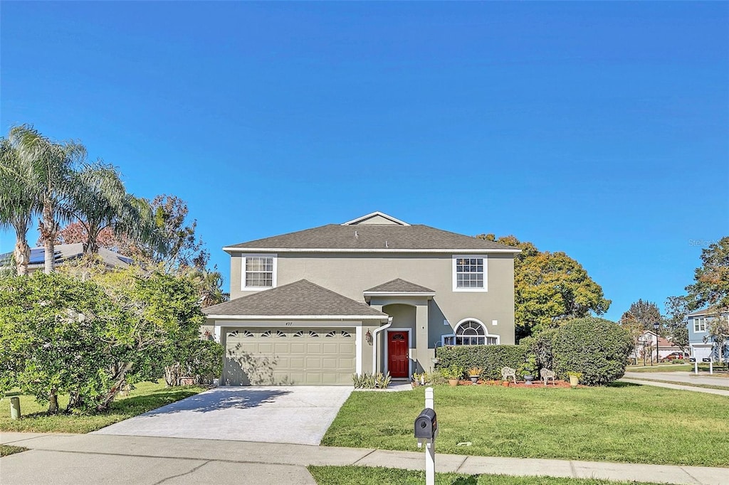 traditional-style house featuring an attached garage, driveway, a front lawn, and stucco siding