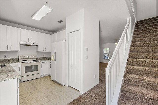 kitchen featuring light carpet, light stone counters, white appliances, ceiling fan, and white cabinets