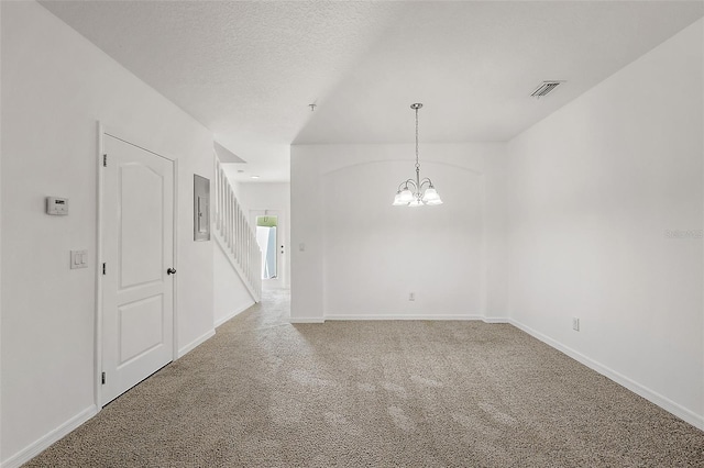 empty room with carpet flooring, a notable chandelier, and a textured ceiling