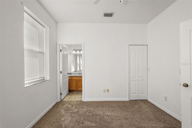 unfurnished bedroom with ensuite bathroom, light colored carpet, and multiple windows