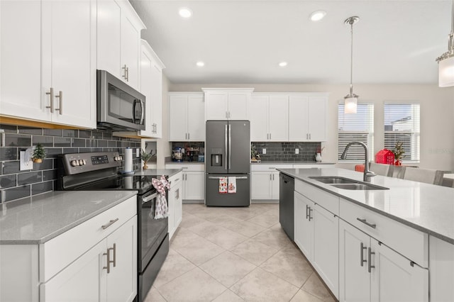 kitchen featuring light stone countertops, white cabinetry, sink, pendant lighting, and appliances with stainless steel finishes