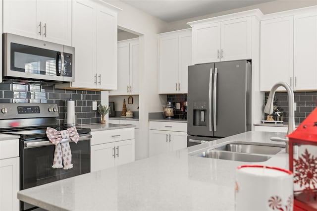 kitchen with backsplash, stainless steel appliances, white cabinetry, and sink