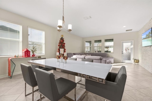 tiled dining space featuring a notable chandelier and a healthy amount of sunlight