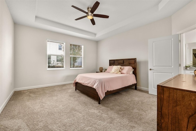 carpeted bedroom featuring ceiling fan and a raised ceiling