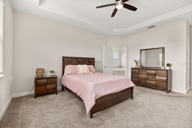 carpeted bedroom featuring ensuite bath, a raised ceiling, and ceiling fan