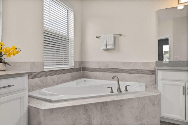 bathroom featuring tiled bath and vanity