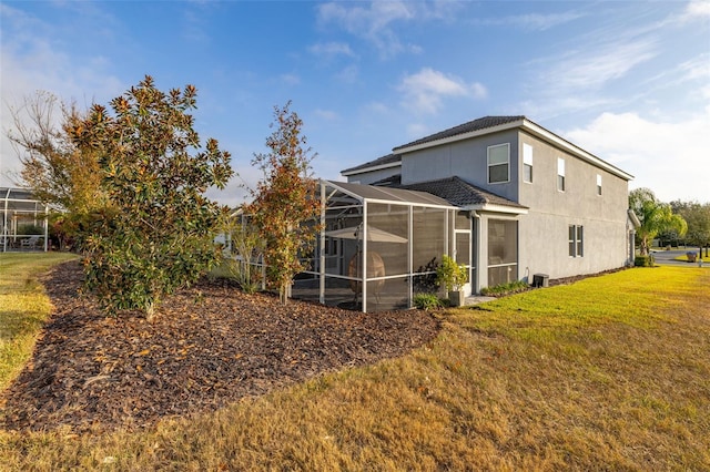 back of property featuring a lawn and glass enclosure