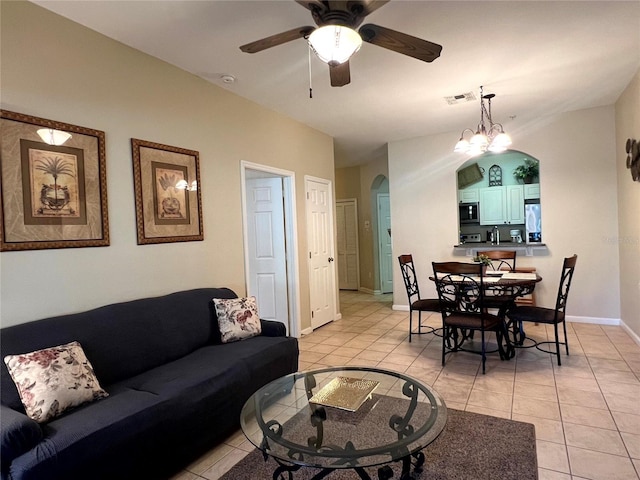 living room with ceiling fan with notable chandelier, vaulted ceiling, and light tile patterned flooring