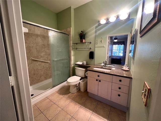 bathroom with tile patterned floors, vanity, a shower with shower door, and toilet