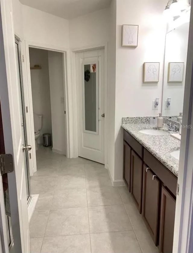 bathroom featuring tile patterned floors, vanity, toilet, and walk in shower