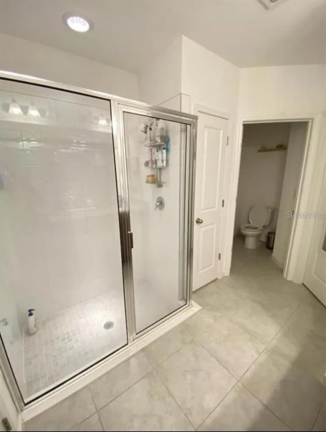 bathroom featuring a shower with shower door and toilet