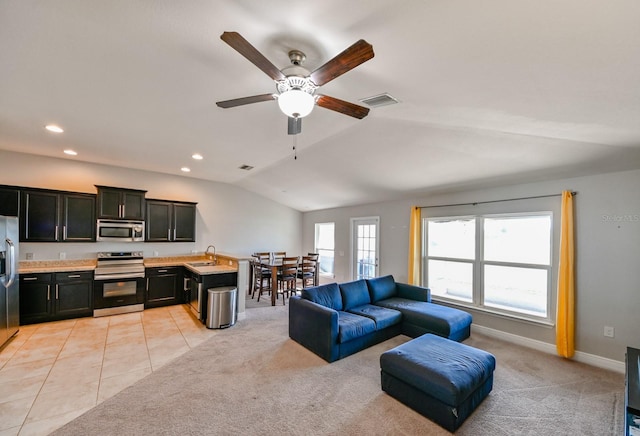 tiled living room with ceiling fan, sink, and vaulted ceiling