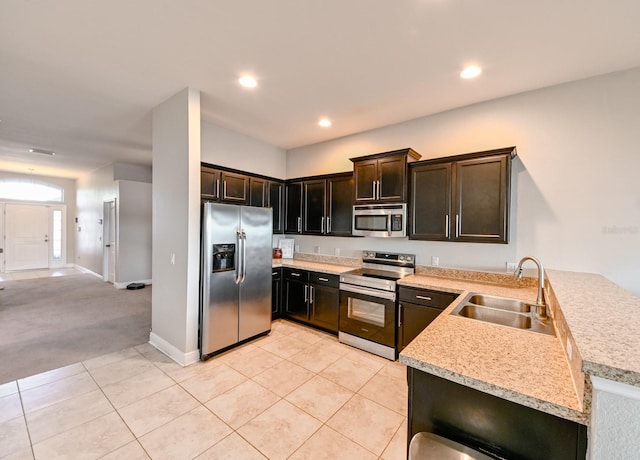 kitchen featuring sink, kitchen peninsula, light tile patterned floors, dark brown cabinetry, and stainless steel appliances