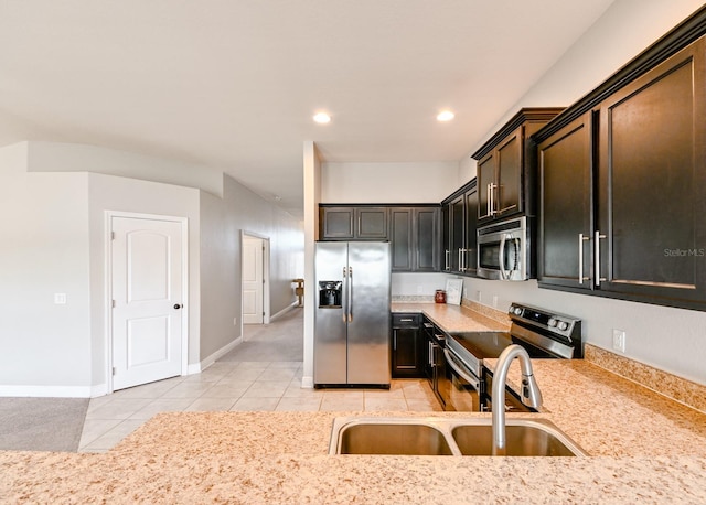 kitchen with sink, light stone countertops, dark brown cabinets, light tile patterned flooring, and stainless steel appliances